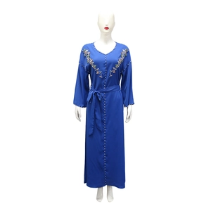 Dettaglio di perline cucite a mano e ricami floreali su un abito abaya blu con scollo a V