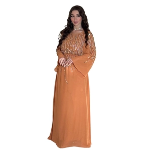 Dettaglio dell'abito da sera in chiffon arancione ambra con paillettes e maniche a campana