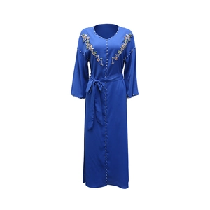 Dettaglio di strass cuciti a mano e ricami floreali su un abito abaya blu scuro con scollo a V