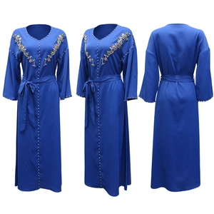 Dettaglio di ricamo floreale e strass argentati su un abito Abaya blu con scollo a V