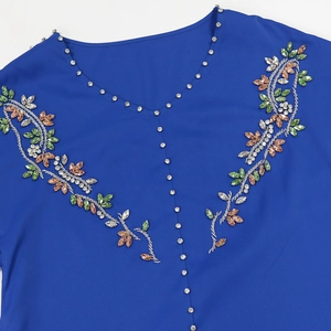 Dettaglio dello scollo a V con strass colorati cuciti a mano su abito blu reale