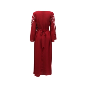 Dettaglio dell'abito in chiffon bordeaux con fiocco in vita e strass sulle maniche