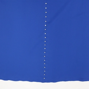 Dettaglio del tessuto blu con decorazioni di strass argentati cuciti a mano