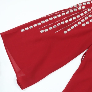 Dettaglio del tessuto in chiffon rosso con strass lucidi sulla manica a campana