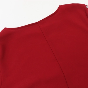 Dettaglio del girocollo di un abito in chiffon rosso con eleganti decorazioni in strass
