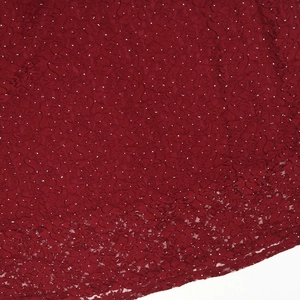 Close-up of red lace fabric with intricate floral patterns and silver sparkling rhinestones