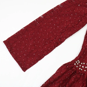 Detailed close-up of dark red lace fabric with sparkling rhinestones and silver sequins