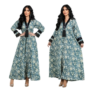 Detailed view of V-neckline with black sequins, lace trim and tassel on printed kaftan dress