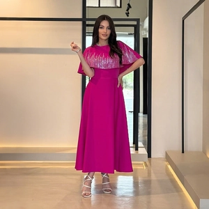 Dettaglio di paillettes argentate su abito da sera magenta con design a mantella