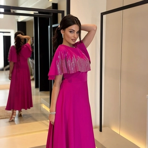 Dettaglio dell'abito magenta con strisce di strass argentati e maniche a mantella