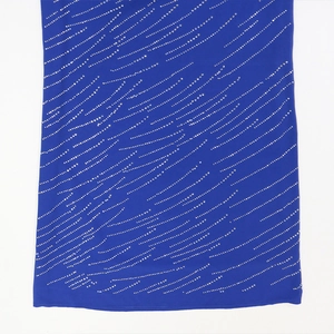 Détail du tissu en mousseline bleu roi avec motifs ondulés de strass scintillants