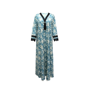 Close-up of V-neckline with black tassel and lace trim on floral print kaftan dress