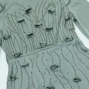 Detailed view of the beaded waist with 3D floral appliques on the sage green silk dress