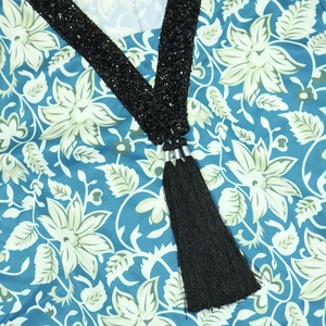 Detail of V-neckline with black sequin embroidery and long tassels on a floral print kaftan