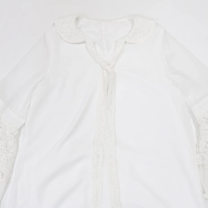 Close-up of lace Peter Pan collar and delicate ribbon tie on white long-sleeve blouse