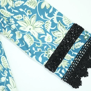 Detail of blue floral dress sleeve with black sequins and delicate lace trim cuff