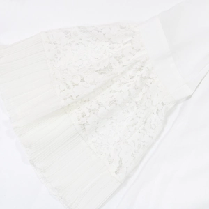 Detailed close-up of white floral lace fabric and delicate pleated trim on the dress