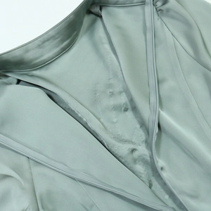 Detail view of the sage green satin dress neckline and discrete invisible zipper closure