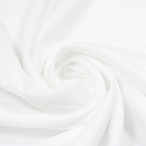 Close-up of white textile fabric with delicate lace texture and elegant draped folds