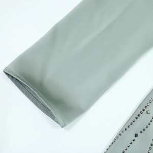 Detail of sage green satin dress featuring intricate beaded studs and fine seam stitching