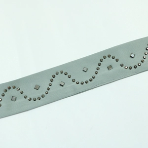 Detail of beaded gray-green satin belt featuring rhinestones and metal rivets for dress