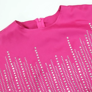 Dettaglio dell'abito in raso rosa con motivi di strass quadrati e scollo rotondo