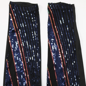 Detail of black mesh arm sleeves with shiny blue and orange sequin vertical stripes