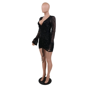 Detail of black sequined mini dress featuring deep V-neck, long sleeves and feather trim