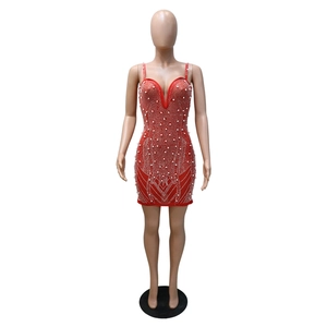 Détail d'une mini-robe rouge moulante avec perles blanches et motifs ondulés en strass