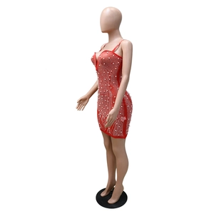 Détail d'une robe moulante rouge ornée de perles blanches et de strass sur le col en V