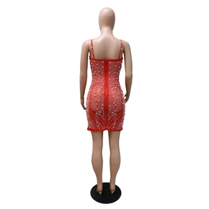 Détail de robe rouge moulante avec perles blanches, paillettes et fermeture éclair au dos