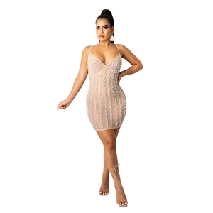 Detailed close-up of mini dress featuring vertical white pearls on beige fabric