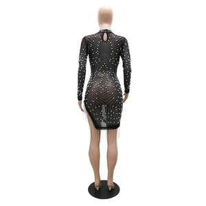Détail de robe en résille transparente avec strass, perles et glands perlés sur l'ourlet