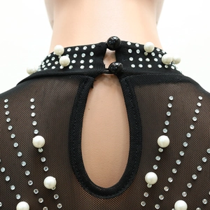 Détail du col d'une robe en résille noire ornée de perles blanches et strass brillants