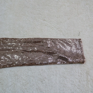 Detailed macro view of rose gold sequin fabric on a long sleeve evening jumpsuit