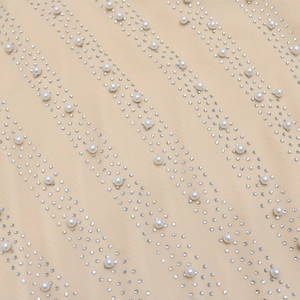 Close-up of mesh fabric with silver rhinestones and white pearls on the mini dress