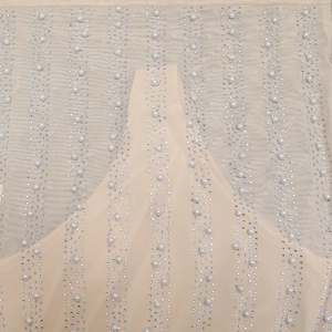 Macro detail of nude mesh fabric featuring vertical rows of silver rhinestones and white pearls