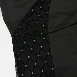 Detail of black mesh fabric with flocked diamond patterns and silver glitter accents