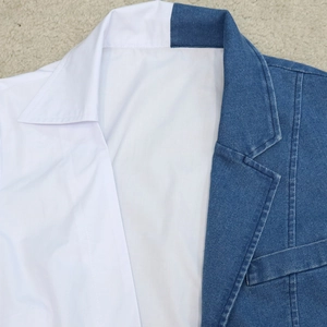 Macro shot of stitching detail on denim and white fabric patchwork V-neck dress