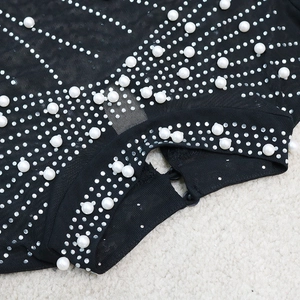 Détail d'une robe en résille noire avec perles blanches et accents de strass brillants