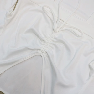 Detailed view of white dress featuring drawstring ruching and triangular cutout detail