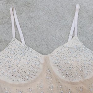 Detail of champagne mini dress featuring hand-sewn pearls and rhinestones on mesh fabric