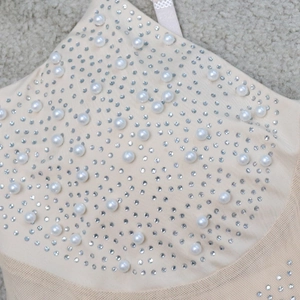 Detail of nude mini dress featuring white pearls and silver rhinestones on mesh fabric