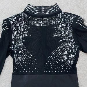 Détail d'une robe de soirée en résille noire avec strass argentés et glands métalliques