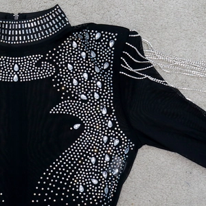Détail d'une combinaison en mesh noir avec strass argentés et franges métalliques sur l'épaule