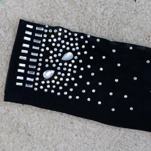 Détail d'un tissu en maille noire transparente avec strass complexes et franges