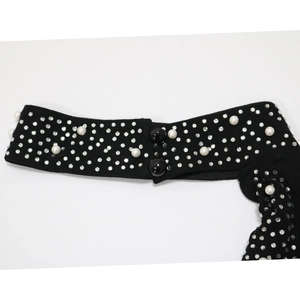 Detail of black fabric neckline decoration with white pearls and sparkling rhinestones