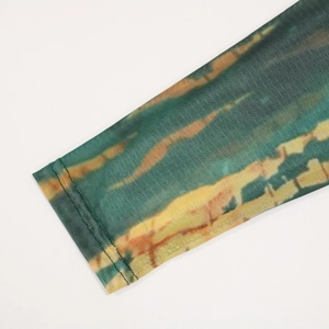 Close-up of sheer mesh sleeve with green and brown tie-dye print and hem details