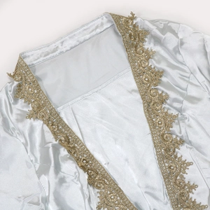 Close-up of golden lace embroidery and metallic patterns on light blue satin dress fabric