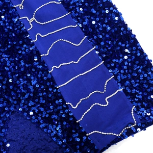 Detail of blue sequin dress featuring silver wavy rhinestone chains on a satin ribbon